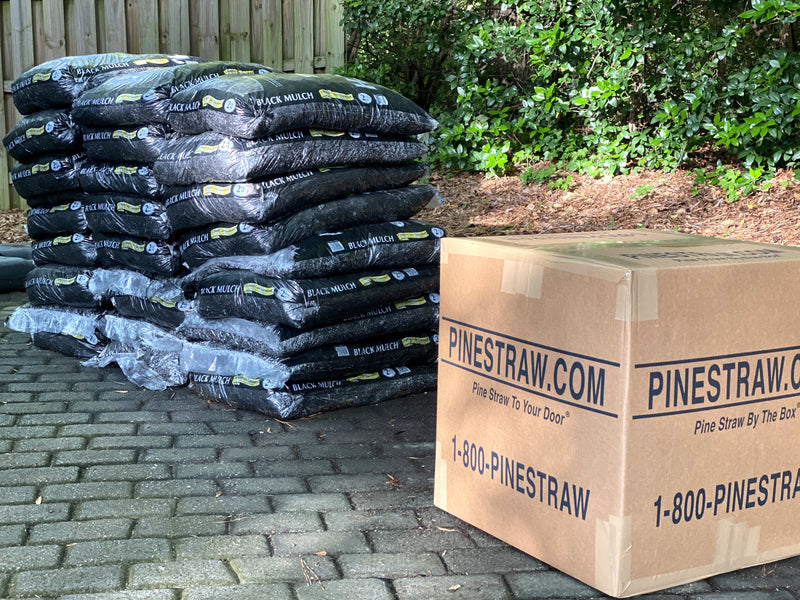 A stack of mulch bags next to one pine straw box